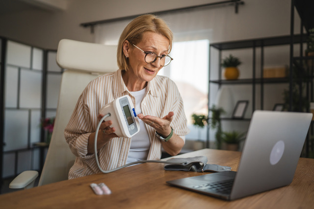 Woman using a blood-pressure cuff on a video call.