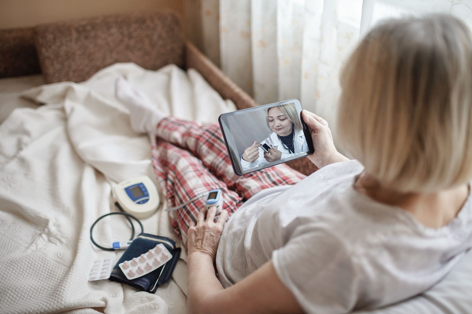 patient at home on a tablet telehealth call with a pulse oximeter and BP cuff